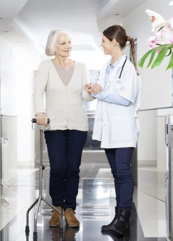 Nurse walking alongside a patient using a walker